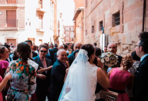Novios de espaldas a la salida de la iglesia rodeados de gente, reportaje de boda Patricia y Miguel