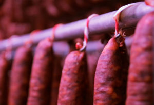 Chorizos colgados sobre barras en proceso de curación. La Familia Cerrillo Fontecha lleva más de un siglo dedicándose en sus orígenes a la cría de ganado y posteriormente a la elaboración y venta de embutidos. Reportaje de Andrea Aragón