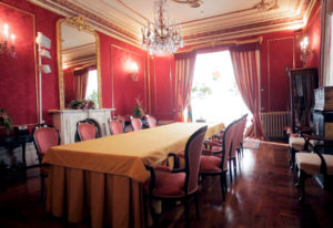 Estancia de Palacio de la Presidencia del Gobierno o La casa de El Inglés. Construido en la segunda mitad de los años sesenta del siglo XIX por encargo de Andrés Isidro Bretón, edificada bajo el estilo de la arquitectura británica de su tiempo. Con paredes y butacas en rojo, techo crema con adornos en dorado. Chimenea blanca bajo un gran espejo con marco dorado. En mitad del techo se encuentra una lámpara de cristales, al igual que en las paredes. Foto y vídeo de Andrea Aragón.